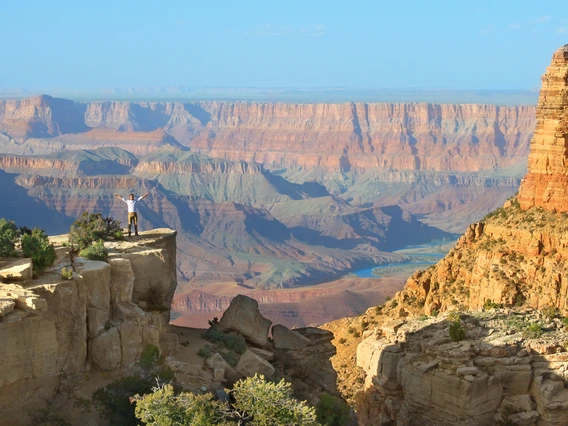 A person stands on a peak near the grand canyon