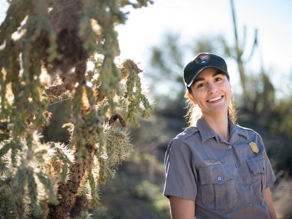 A woman smiling standing next to a cactus