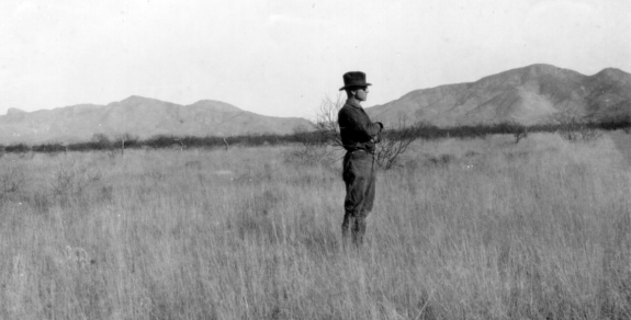 A man stands in the grasslands at the Santa Rita Experimental Range, May 1920